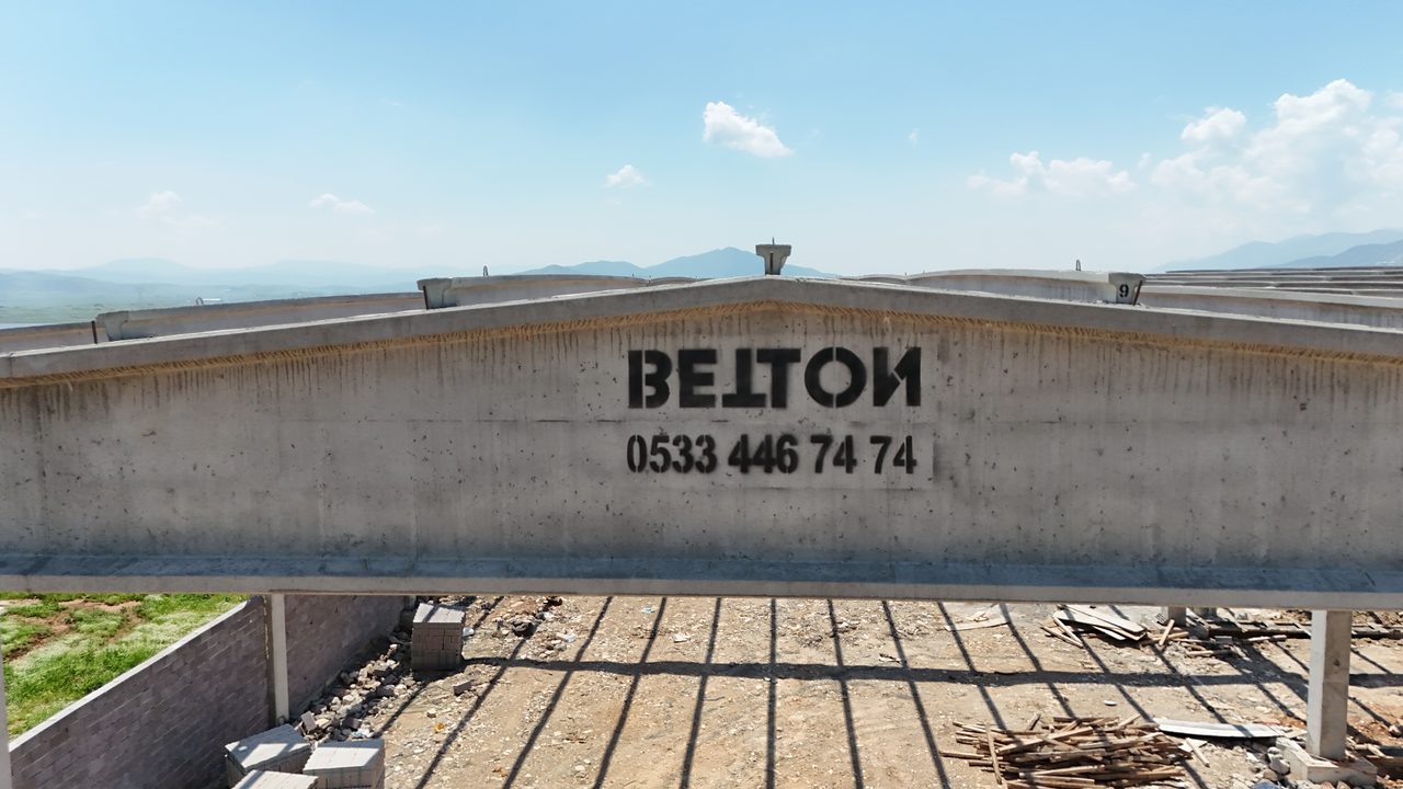 Prestressed roof girder stamped with the BETTON mark, with purlins and the valley behind it.