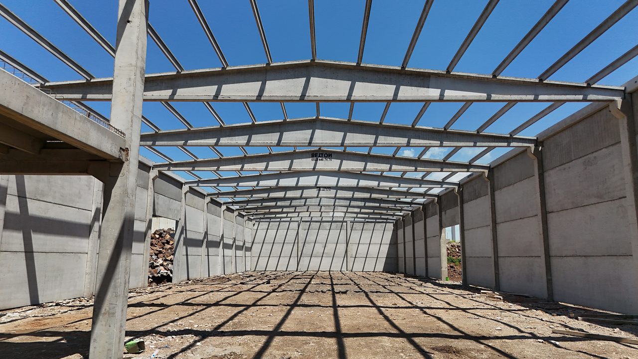 Interior of the industrial hall: precast wall panels, columns and a long row of roof girders.